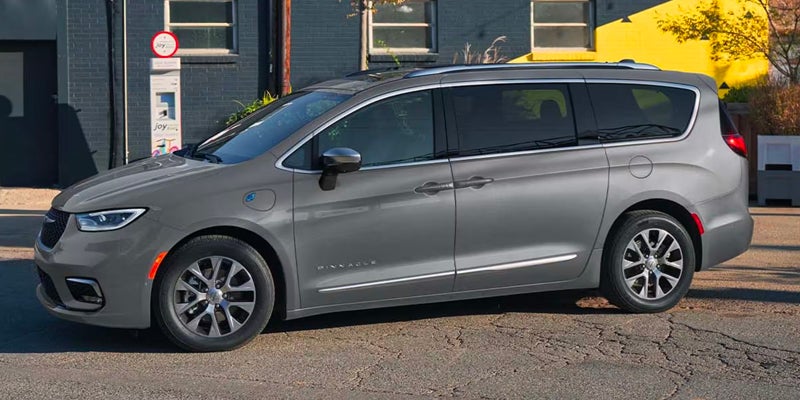 Silver Chrysler Pacifica minivan parked on a city street, shown in side profile