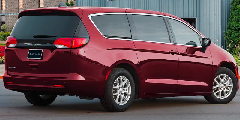 Rear three-quarter view of a red minivan parked outside a commercial building.