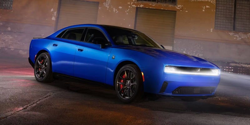 Blue Dodge Charger Daytona electric muscle car parked on a wet city street at night