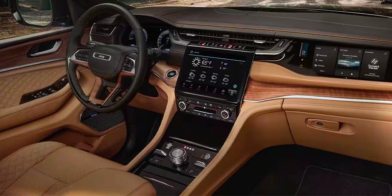 Modern tan leather car interior with wood trim, large central touchscreen, and digital displays