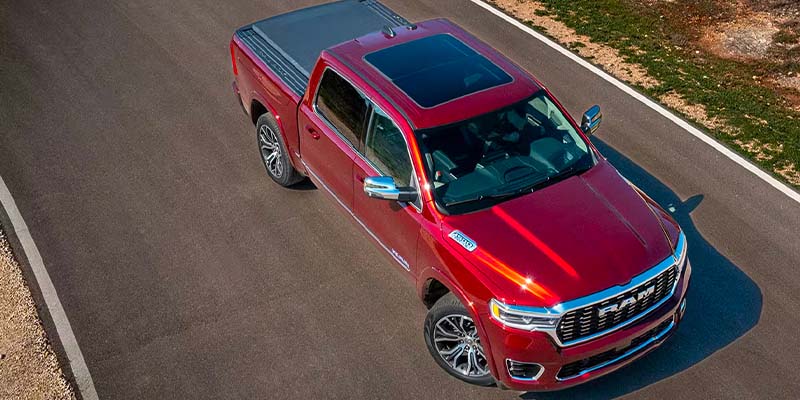 Overhead front-angle view of a red Ram pickup truck driving on a paved road