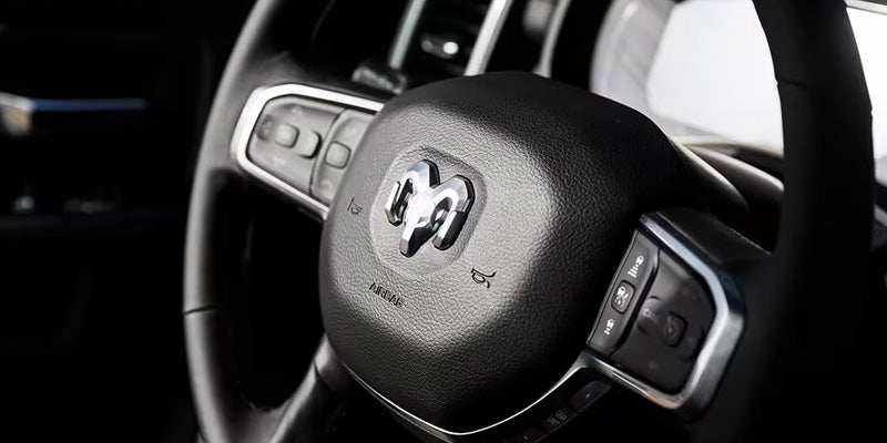 Close-up of a Ram-branded steering wheel showing integrated control buttons inside the vehicle cabin