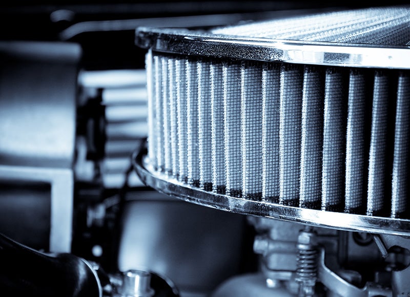 Close-up view of an automotive air filter inside an engine compartment, showing pleated filter material
